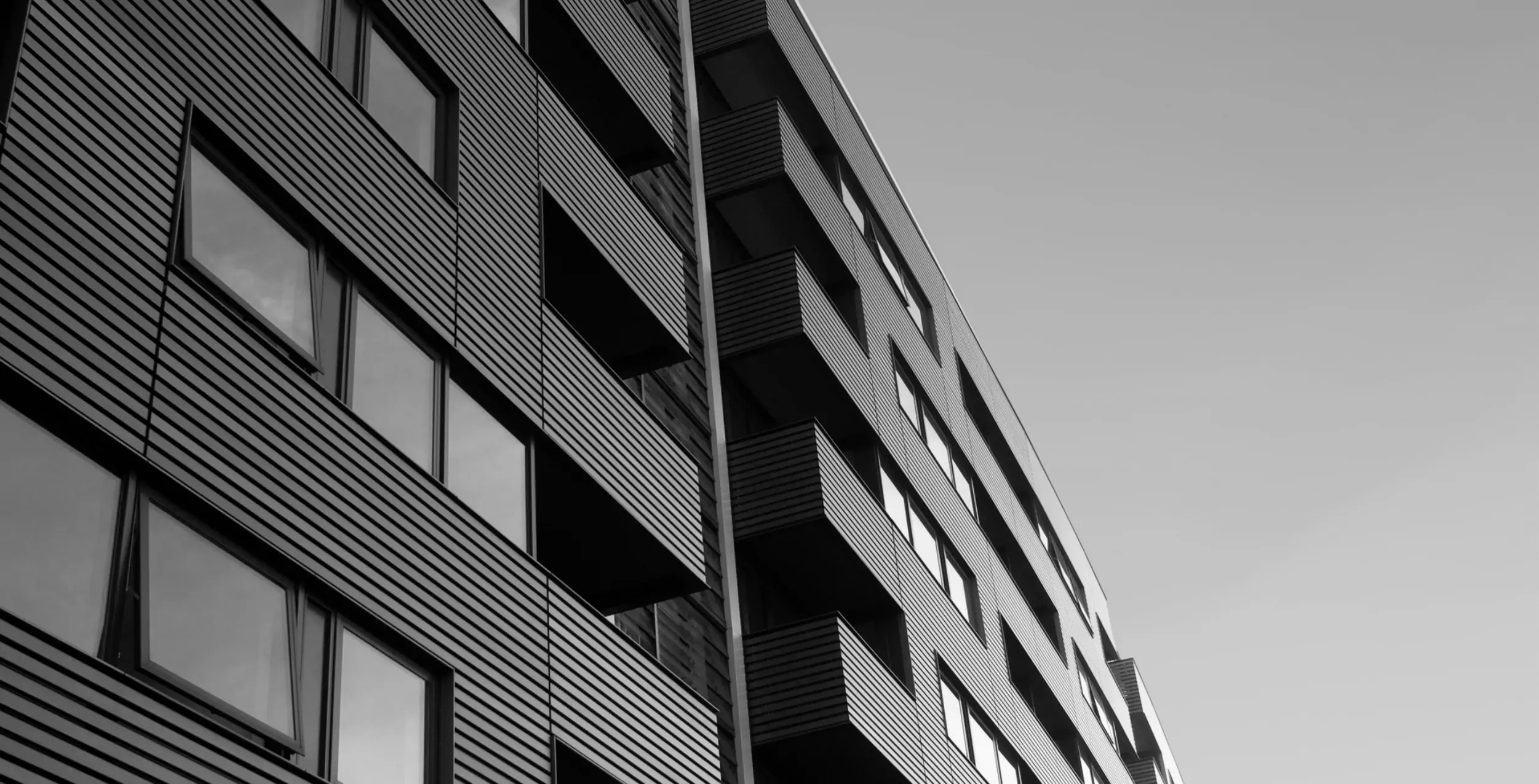 A black and white still of the side of a high building structure.