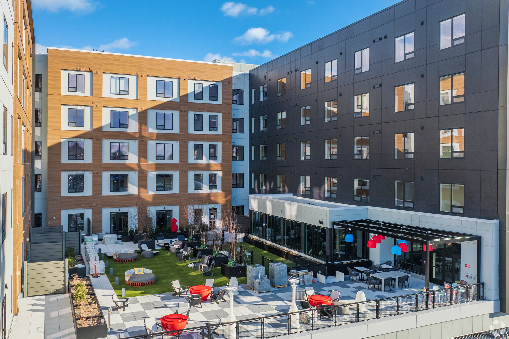 Courtyard of The Cove in Worcester, MA, with outdoor seating, artificial grass, and colourful light fixtures.