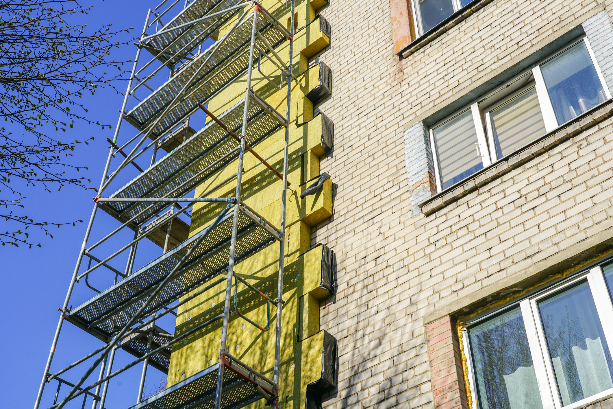 Residential apartment building retrofit showing external wall insulation installation to reduce thermal bridging and heat loss