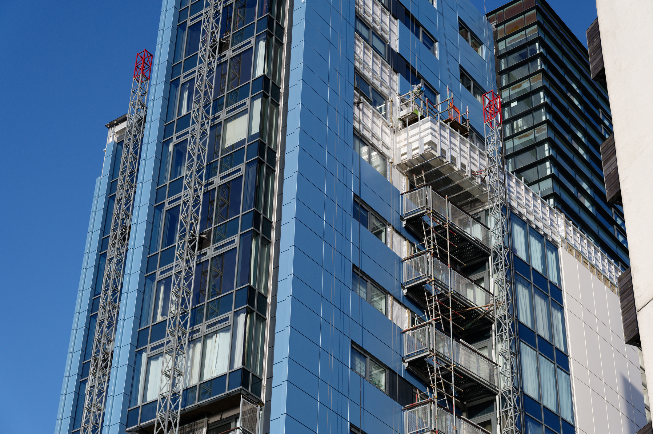 Commercial building facade retrofit with new cladding panels and access platforms to improve envelope performance and reduce heat loss